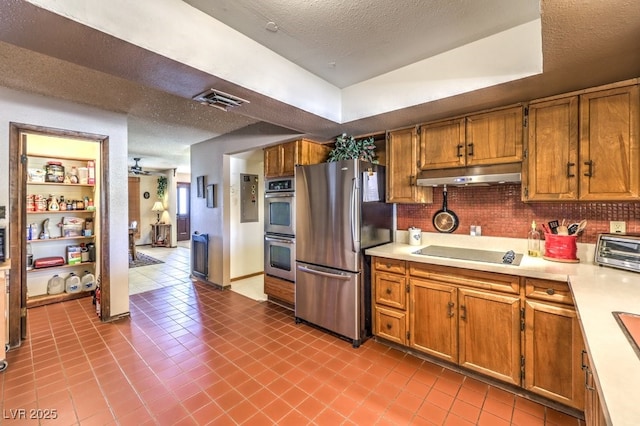 10615 Rancho Destino Rd, Las Vegas, NV 89183 - kitchen with under cabinet range hood, brown cabinetry, appliances with stainless steel finishes, and light countertops