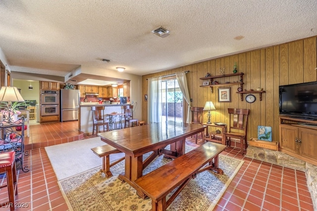10615 Rancho Destino Rd, Las Vegas, NV 89183 - living area featuring tile patterned floors, visible vents, wood walls, and a textured ceiling