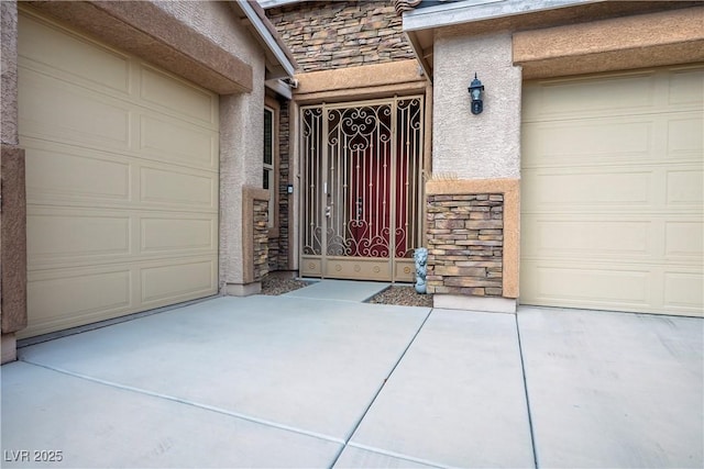 view of exterior entry with a garage, stone siding, driveway, and stucco siding