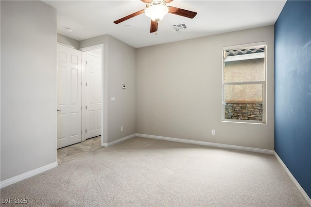 empty room featuring visible vents, carpet, baseboards, and ceiling fan