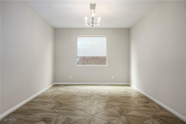 unfurnished room with baseboards and an inviting chandelier