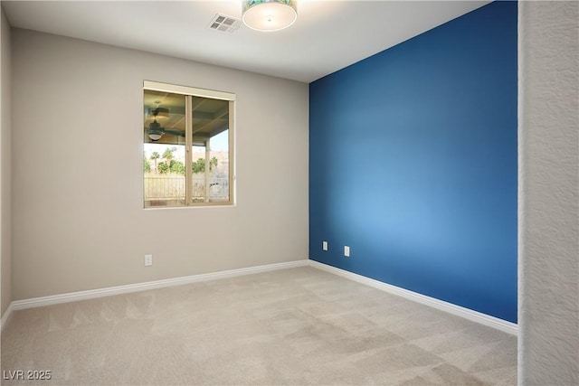 carpeted spare room featuring visible vents, baseboards, and a ceiling fan