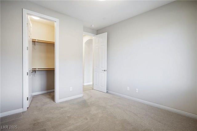 unfurnished bedroom with a closet, baseboards, a walk in closet, and carpet