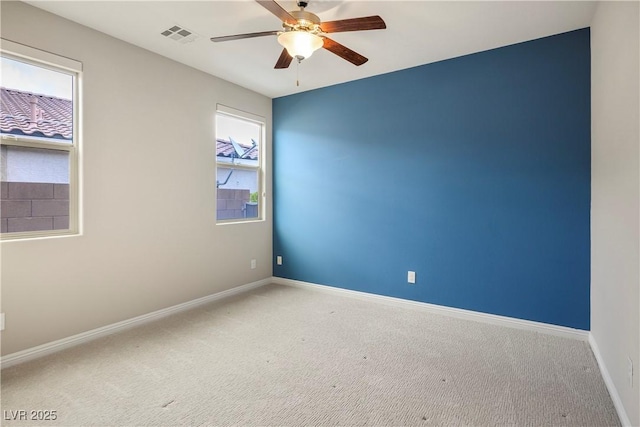 carpeted empty room featuring baseboards, visible vents, and ceiling fan