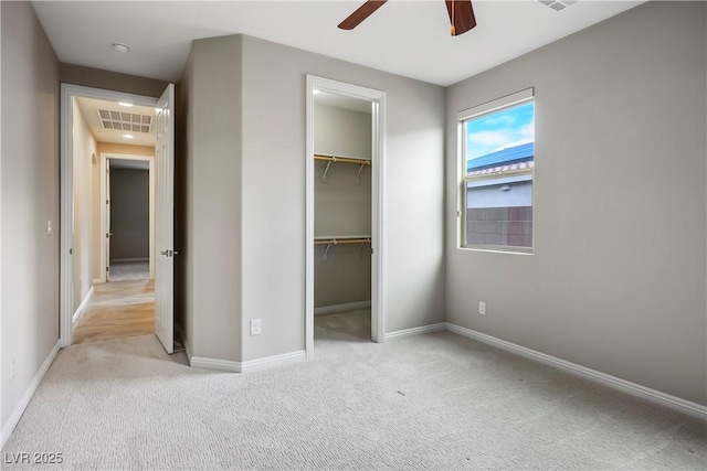 unfurnished bedroom featuring visible vents, baseboards, a walk in closet, and carpet flooring