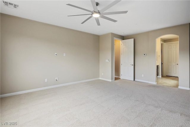 unfurnished bedroom featuring visible vents, baseboards, light colored carpet, arched walkways, and a ceiling fan