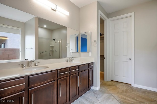 bathroom featuring an enclosed shower, a sink, a walk in closet, and double vanity