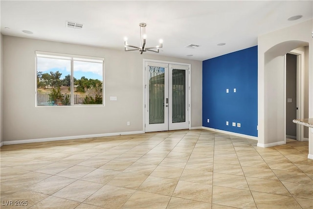 empty room featuring arched walkways, visible vents, french doors, and a chandelier