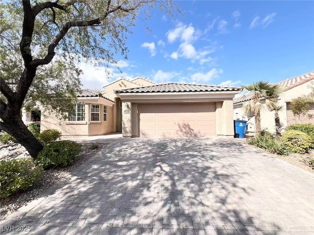 view of front of property with a tile roof, decorative driveway, a garage, and stucco siding