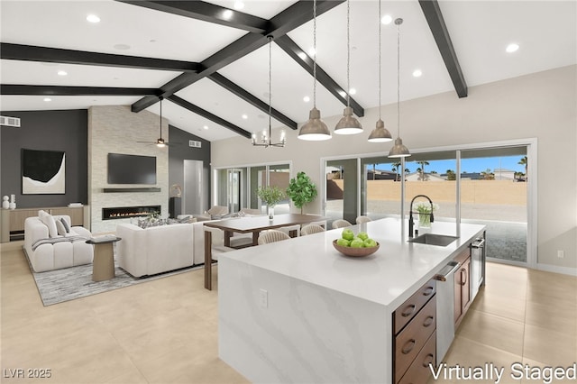 kitchen featuring a sink, decorative light fixtures, a wealth of natural light, and an island with sink