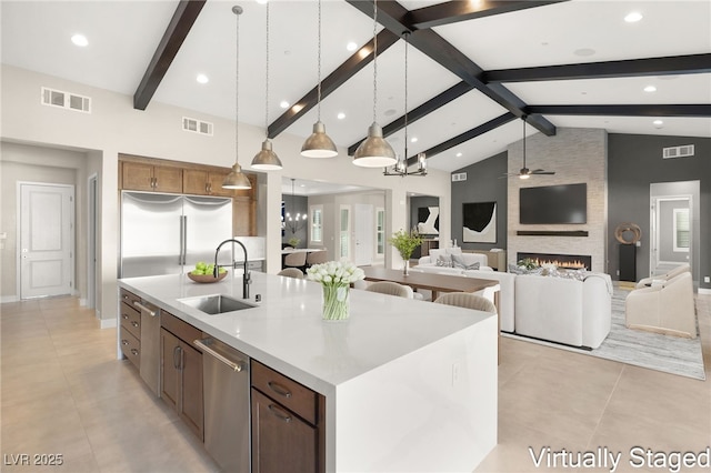 kitchen with visible vents, a ceiling fan, a sink, stainless steel appliances, and a fireplace