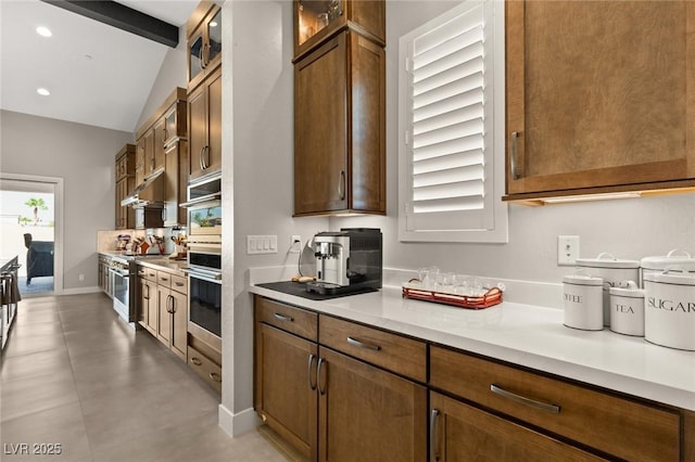 kitchen with glass insert cabinets, lofted ceiling with beams, light countertops, recessed lighting, and stainless steel appliances