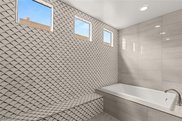 full bath with a garden tub, tile walls, and a tile shower