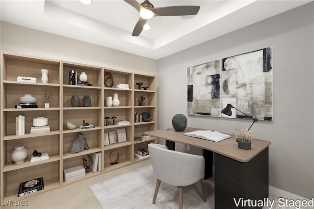 tiled home office featuring a raised ceiling and a ceiling fan