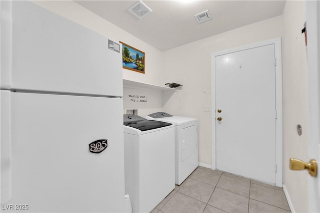 clothes washing area featuring visible vents, independent washer and dryer, light tile patterned flooring, and laundry area