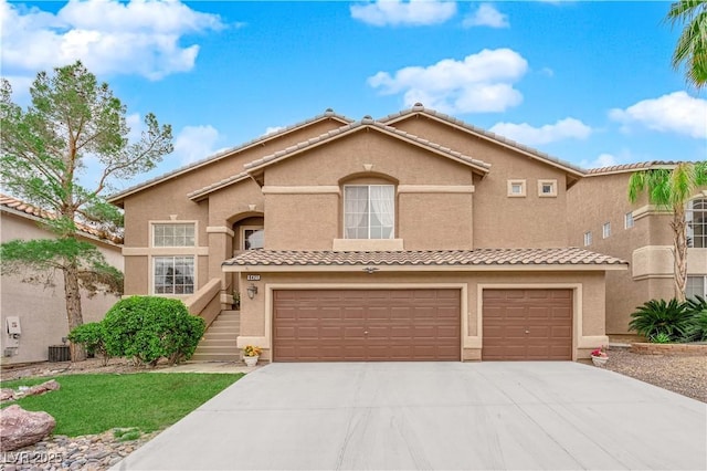 view of front of home with concrete driveway, a tiled roof, a garage, and stucco siding