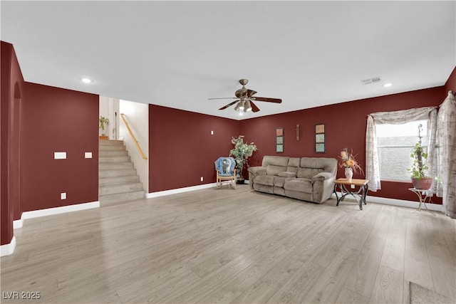 living room with stairway, visible vents, baseboards, light wood finished floors, and ceiling fan