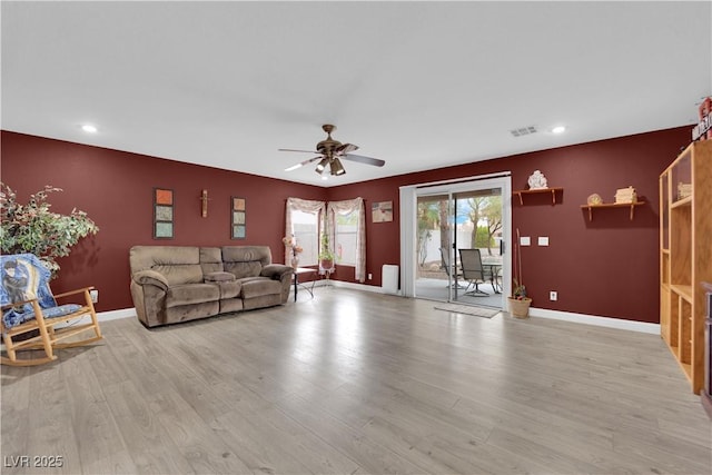 living area with a ceiling fan, light wood-type flooring, and baseboards