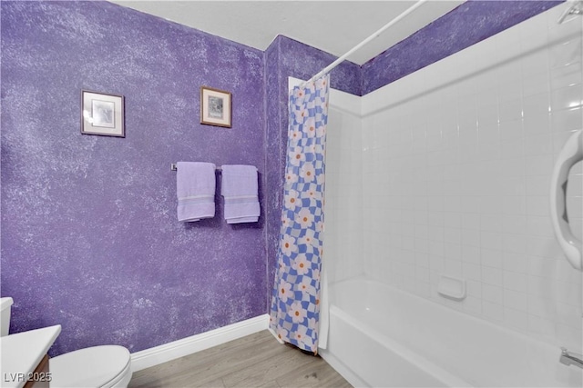 bathroom with vanity, wood finished floors, baseboards, shower / bath combo with shower curtain, and toilet