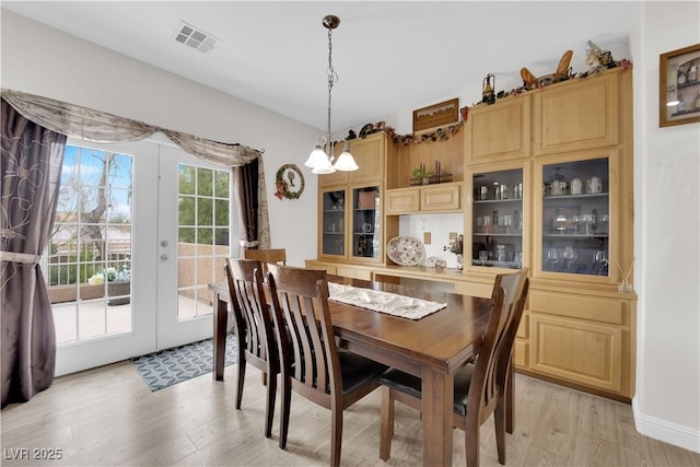 dining area featuring visible vents, an inviting chandelier, light wood-style flooring, and french doors