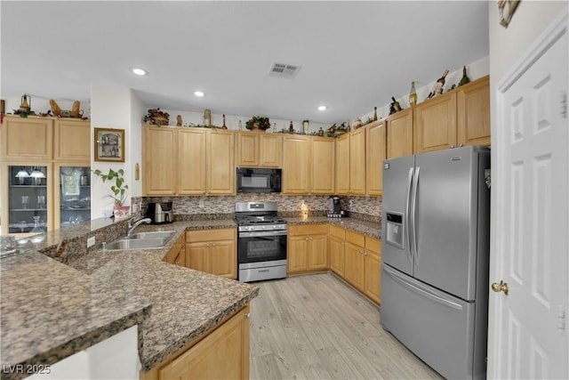 kitchen featuring a sink, stainless steel appliances, backsplash, and light brown cabinetry