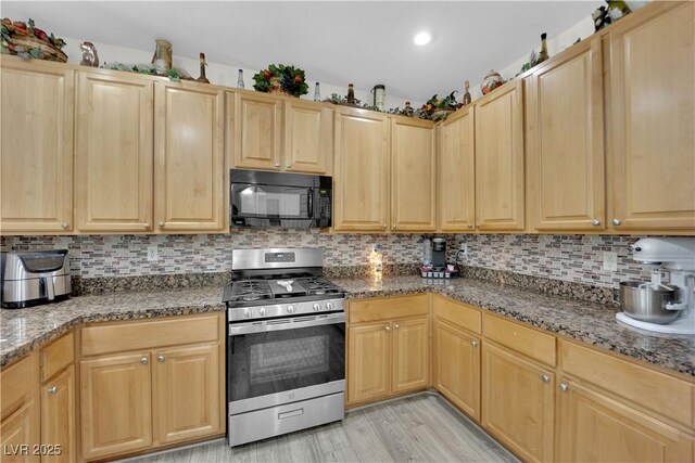 kitchen with stainless steel gas stove, tasteful backsplash, black microwave, and light brown cabinetry