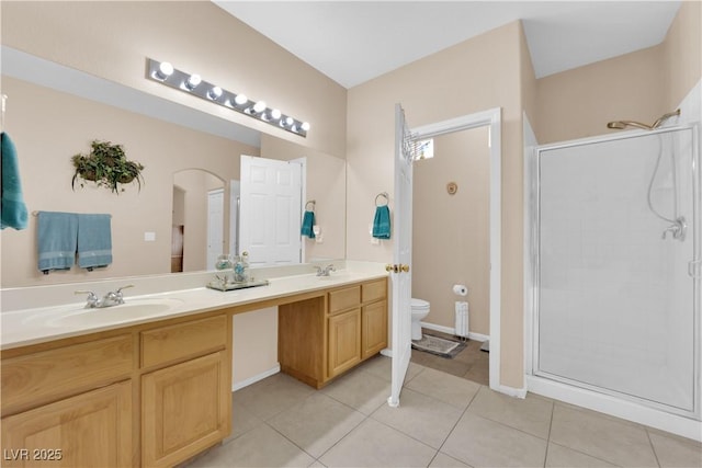 full bathroom with double vanity, a stall shower, a sink, tile patterned floors, and toilet