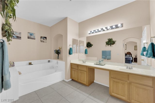 ensuite bathroom with tile patterned flooring, a garden tub, double vanity, ensuite bath, and a sink