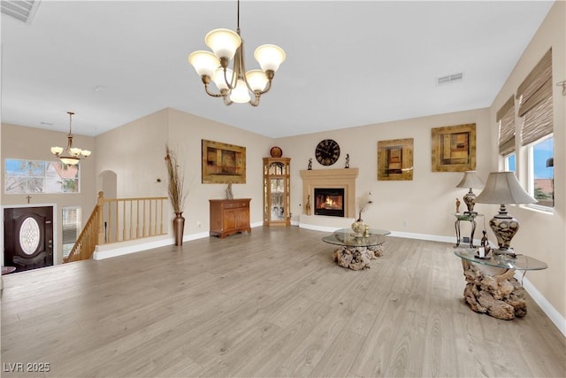 living area with a chandelier, visible vents, a glass covered fireplace, and wood finished floors