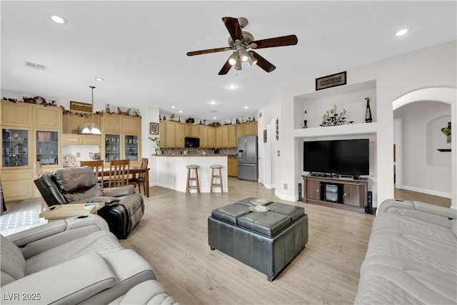 living room featuring recessed lighting, light wood-style flooring, arched walkways, and ceiling fan