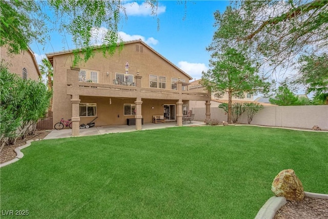 rear view of house with a balcony, a fenced backyard, stucco siding, a patio area, and a lawn