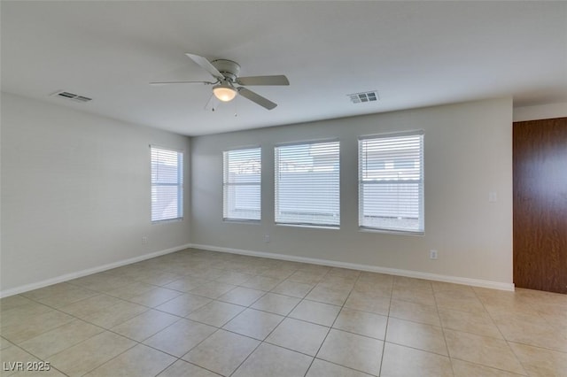 empty room featuring light tile patterned floors, baseboards, visible vents, and ceiling fan