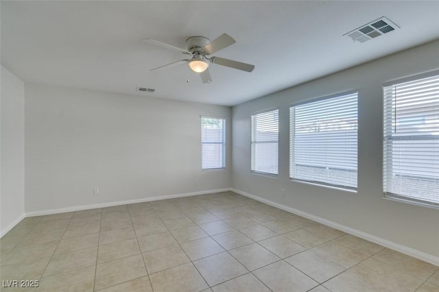 spare room featuring a ceiling fan, visible vents, and baseboards