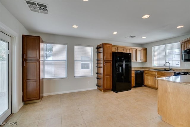 kitchen with a wealth of natural light, visible vents, black appliances, and a sink