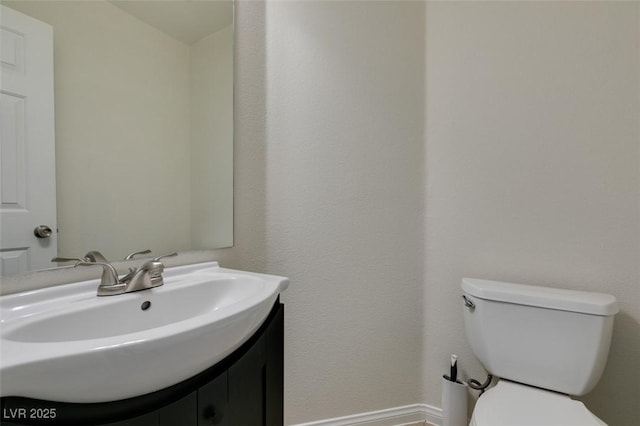 half bath with baseboards, toilet, and vanity