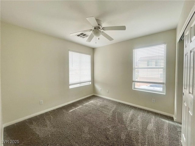 carpeted spare room featuring visible vents, baseboards, and a ceiling fan