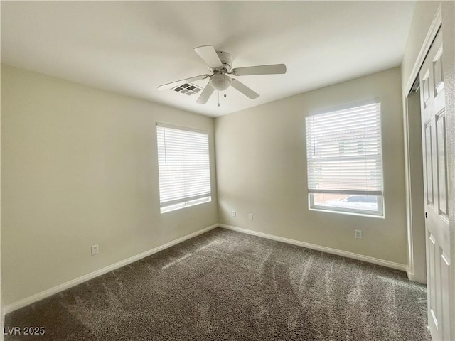 unfurnished room with visible vents, carpet floors, a healthy amount of sunlight, and ceiling fan