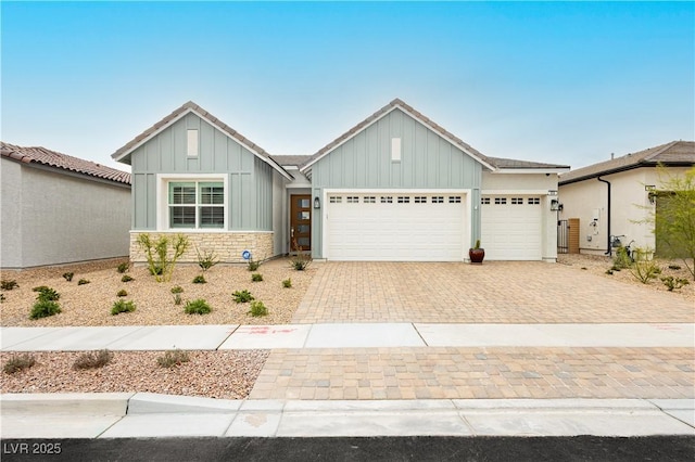 view of front of home with an attached garage, decorative driveway, and board and batten siding