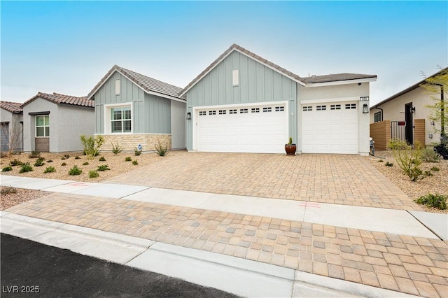 view of front of house with fence, an attached garage, a tiled roof, decorative driveway, and board and batten siding