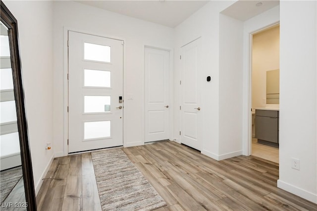 entryway featuring baseboards, a healthy amount of sunlight, and light wood-style flooring