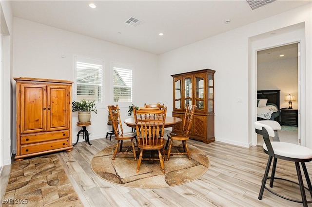 dining space featuring light wood-type flooring, visible vents, and baseboards