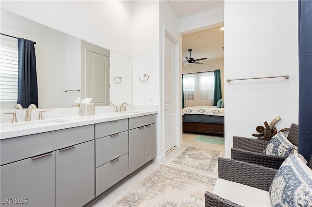 ensuite bathroom featuring double vanity, connected bathroom, a ceiling fan, and a sink