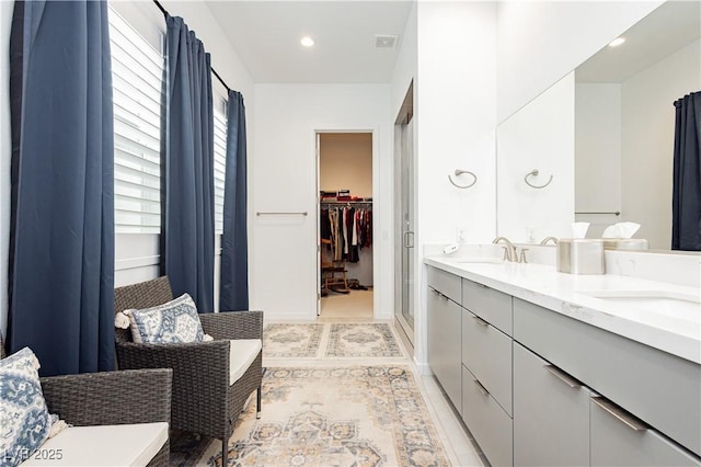 full bath featuring a walk in closet, double vanity, visible vents, and a sink