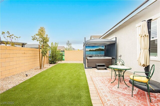 view of yard with a patio area, a fenced backyard, and a hot tub