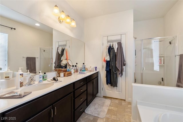 bathroom featuring double vanity, stone finish flooring, a stall shower, and a sink