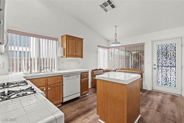 kitchen featuring visible vents, a sink, tile countertops, white dishwasher, and vaulted ceiling