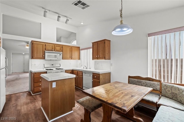 kitchen with visible vents, a kitchen island, white appliances, decorative backsplash, and tile counters