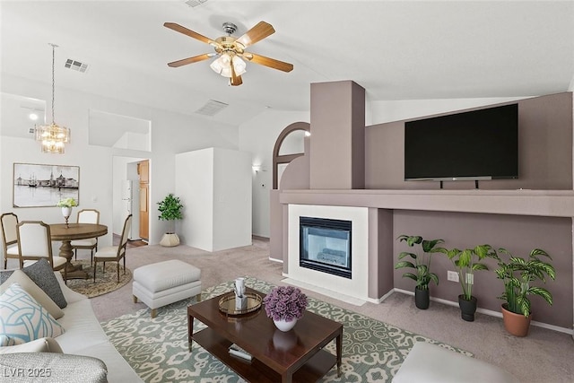 living room featuring visible vents, carpet flooring, lofted ceiling, and a glass covered fireplace