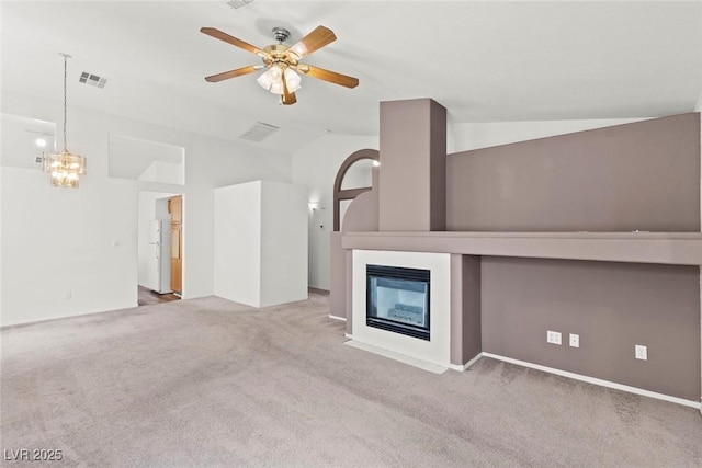 unfurnished living room with visible vents, carpet, a fireplace with flush hearth, vaulted ceiling, and ceiling fan with notable chandelier