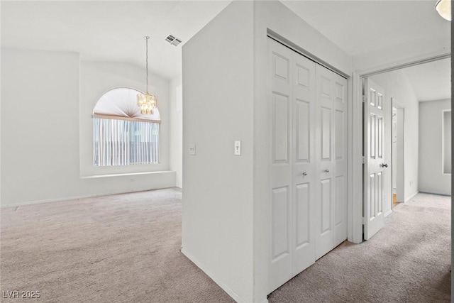 hallway with vaulted ceiling, visible vents, carpet floors, and a chandelier